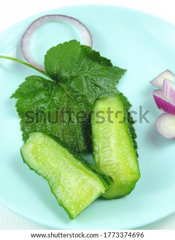    salted cucumbers on a currant leaf with red onion  , selective focus  