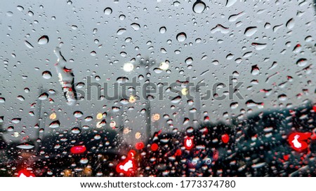 Driving in rain. Rain drop on the car glass background. Abstract traffic in raining day. View from car seat. Road view through car window with rain drops, selective focus. 