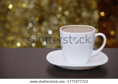 White cup of coffee with milk, lights glittering bokeh. Celebrate, Christmas, New Year, holiday party background.