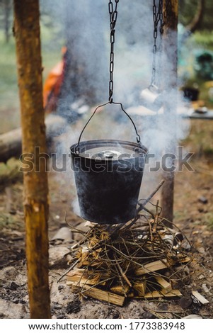 Cooked food on a campfire on a camping trip. camping kitchen, cooking in the forest on fire. A bowler hat over a fire. Camping life concept.