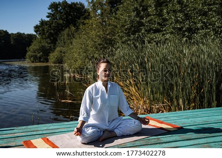 a young girl does yoga on a lake on a Sunny summer day, meditation, relaxation pose, Shavasana or dead man's pose, retreat in nature, peace, relaxation