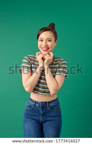 Portrait of young Asian girl posing over green background.