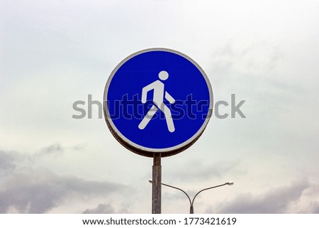 Blue and white round caution road sign for walkway zone and pedestrians
