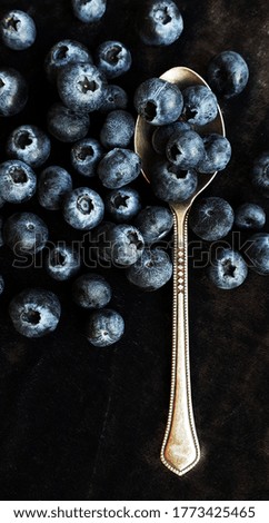 Flat lay composition with blueberries in a metal spoon on a dark background. Appetizing background. Vertical picture.