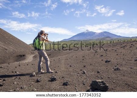Woman nature Photographer taking pictures outdoors during hiking trip on Teide, Tenerife, Canary Islands.