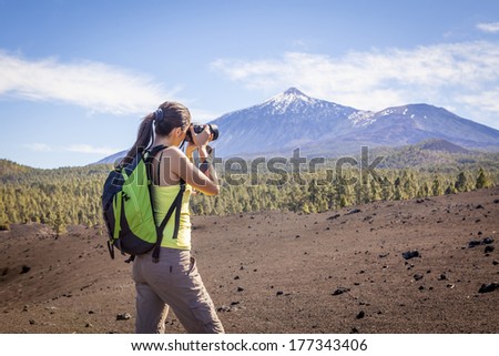 Woman nature Photographer taking pictures outdoors during hiking trip on Teide, Tenerife, Canary Islands.