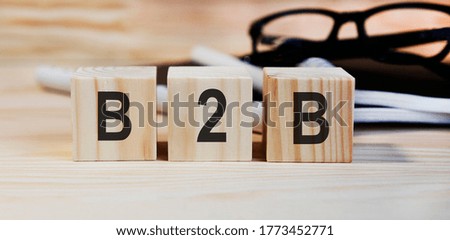 On wooden cubes the inscription B2B, on the background glasses and books.