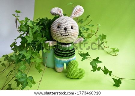 Green crochet bunny, cute rabbit with ivy (Hedera Helix) leaves background, green pastel, light green, eco friendly, botany,