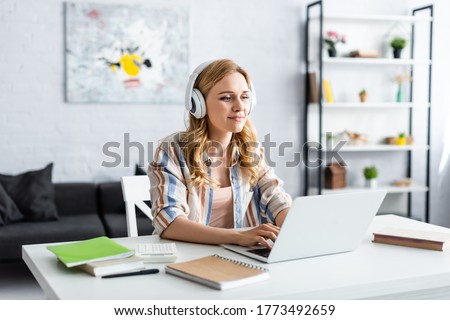 Selective focus of pretty woman working with laptop and headphones Royalty-Free Stock Photo #1773492659
