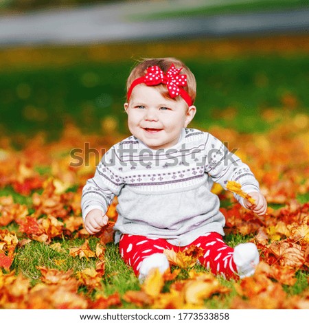 Adorable little baby girl in autumn park on sunny warm october day with oak and maple leaf. Fall foliage. Family outdoor fun in fall. child smiling