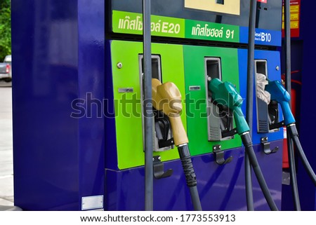 Fuel nozzles at the gas station, Thai language above green nozzle is gasohol 91, above chartreuse green nozzle is gasohol E20, and above blue nozzle is diesel B10 in English. Royalty-Free Stock Photo #1773553913