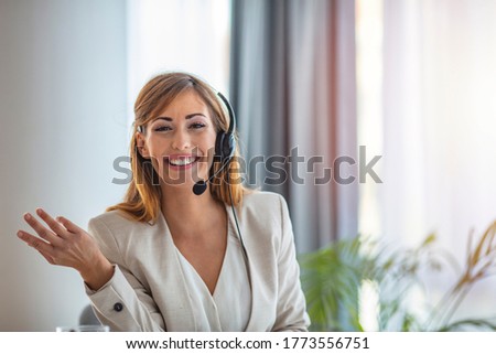 Shot of young agents working in a call center. Happy young woman in headset looking at camera and smiling while sitting at her working place. Cute business customer service woman smiling
