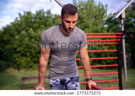 A strong and muscular man trains at an outdoor gym. Street workout