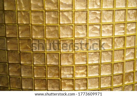 Yellow Glass checkered block. Golden glass or mosaic smalt with yellow filling of seams. Abstract geometric texture or background.