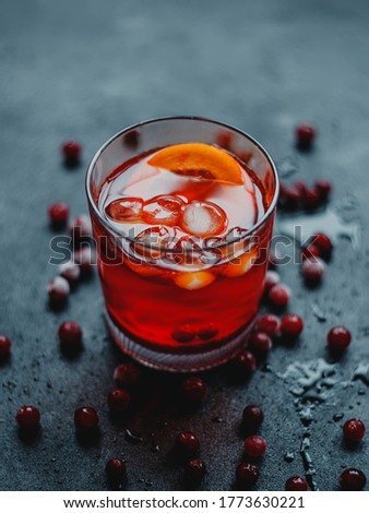 Aperol Spritz with ice and cranberries on a black background.