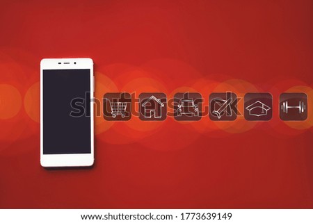 Mockup image of white mobile phone, various icons for financial savings or spending on red background with blank black screen and bokeh