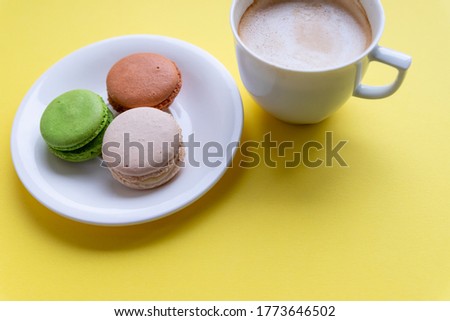 Set of colorful macaroons and coffee.Pastries, confectionery and coffee cup with splash. cookies, macaroons and coffee cupon yellow background. Patisserie shop. good morning card. Copy space