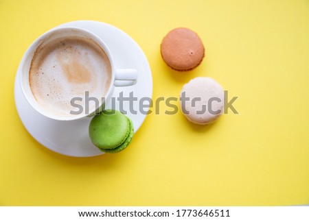 Set of colorful macaroons and coffee.Pastries, confectionery and coffee cup with splash. cookies, macaroons and coffee cupon yellow background. Patisserie shop. good morning card. Copy space