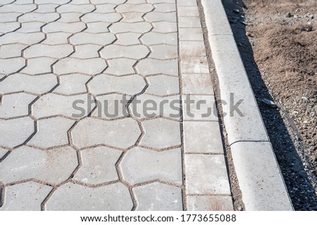 New sidewalk with flat curb and gray paving stone