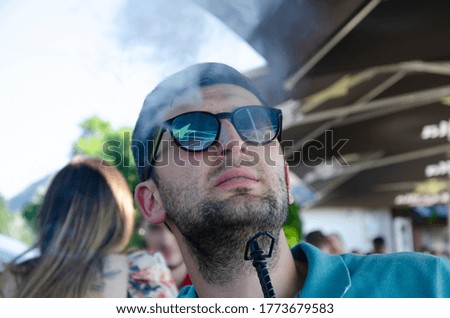 Young Man Smoking Shisha in outdoor Restaurant - Man Exhaling Smoke Inhaling From A Hookah