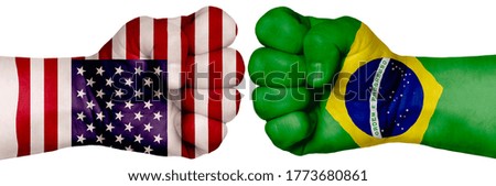 The concept of the struggle of peoples. Two hands are clenched into fists and are located opposite each other. Hands painted in the colors of the flags of the countries. Brazil vs USA