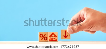 concept of reducing interest rates on mortgages. wooden blocks with house, percent and down arrow icon