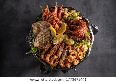 Mixed Seafood Contain Blue Crabs, Mussels, Big Shrimps, Calamari Squids and Grilled Barracuda Fish Garlic with Lemon on Dish Royalty-Free Stock Photo #1773695441