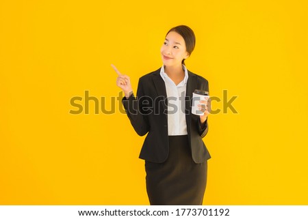 Portrait beautiful young business asian woman with smart mobile phone and coffee cup on yellow isolated background