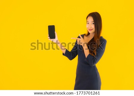 Portrait beautiful young asian woman with smart mobile phone or cellphone on yellow isolated background