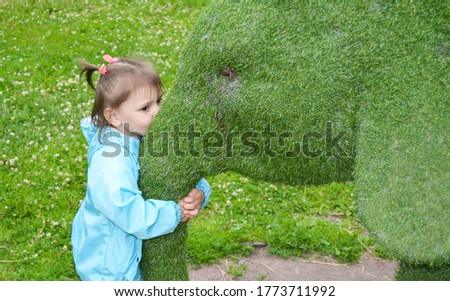 little child, girl hugs a toy elephant from the grass. Love nature concept