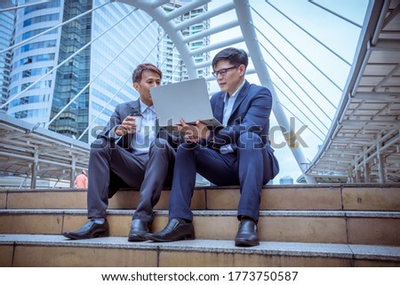Businessmen sit on stair working with laptop discussed together about business plan with happy face.