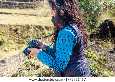 Young woman, a professional photographer, reviewing and checking images she has taken while sitting in the beautiful green grass