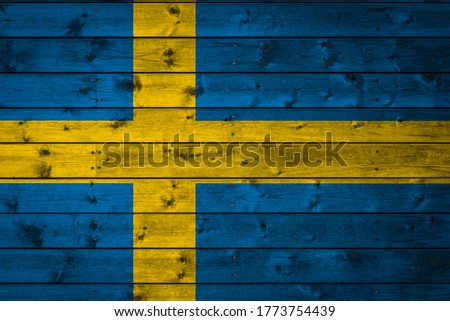 The national flag of Sweden is painted on a camp of even boards nailed with a nail. The symbol of the country.