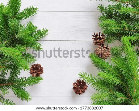 Fir borders and pine cones on white wooden background. Top view of Christmas frame, place for your text or product. Close-up, Christmas flat lay