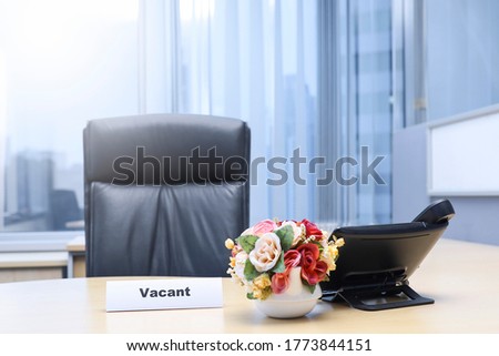 View from front of text on vacant on the office desk, a flower, telephone and arm chair 