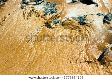 Splashing, foaming white backwash from the Indian Ocean waves breaking on basalt rocks at Ocean Beach Bunbury Western Australia on a sunny afternoon in winter creates patterns in the wet sand.