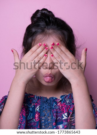 Little pretty cool young girl closes eyes . pink background