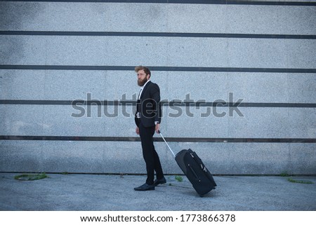 A businessman at the airport pulls a suitcase behind him