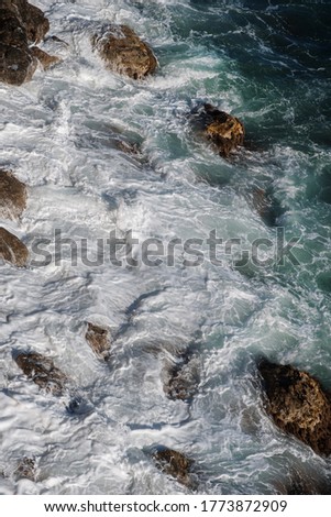 Ocean wave background breaking sea water rocky shore rough seas turquoise water gradient foam. Big waves at open sea. Summer monsoon. White crest of a sea wave.