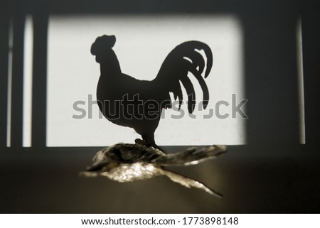 figurine of a rooster that casts a shadow