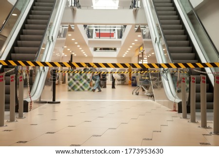 Black and yellow lines of barrier tape prohibit access to supermarket. Barrier tape in shopping center. Barrier that prohibits movement on escalators. Warning. Danger of an unsafe area do not enter