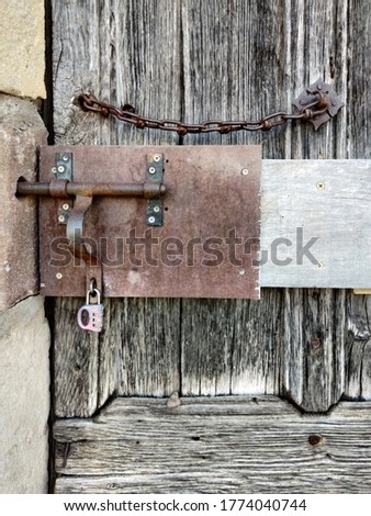 Detail of wooden old locked door in stone wall with ivy