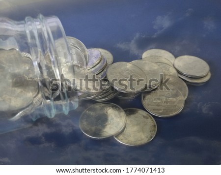 Money coins and blur cloudy sky in the background, concept about your cannot bring money with you to heaven.