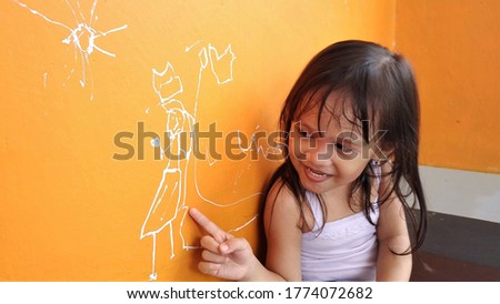 Photo of a little girl who feels happy after drawing on the wall
