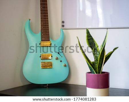modern blue electric guitar in minimalist room corner with snake plant