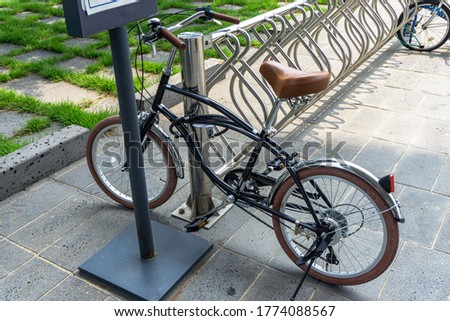 Glossy black vintage bicycle parks at the bicycle park with anti-theft bike lock cable hook up to the stainless bar.