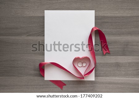 Blank wedding invitations. Photo sheet, ribbon with heart and rings on textured wood background