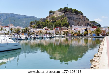 Waterside view to moored yachts at harbour, old famous Denia Castle located on rocky hilltop mountain. Heart of ancient city, landmark and tourism concept. Alicante province, Costa Blanca, Spain Royalty-Free Stock Photo #1774108415