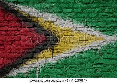colorful painted big national flag of guyana on a massive old brick wall