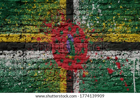 colorful painted big national flag of dominica on a massive old brick wall